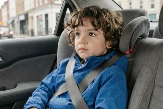 Enfant de 8 ans assis dans un réhausseur homologué avec ceinture de sécurité dans la voiture familiale